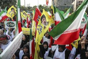 12日、イラン・テヘランで国旗などを手に広場に集まった人たち(ゲッティ=共同)