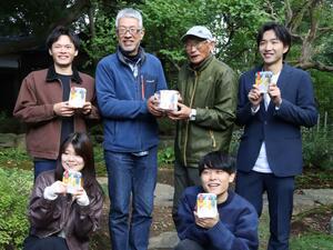 完成したパックご飯を手にポーズを決める伊藤春雄さん（後列左から２人目）と学生ら＝新潟市