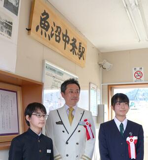 魚沼中条駅に掲げられた駅名看板。右は揮毫した目黒珠音さん=11月17日、十日町市中条甲