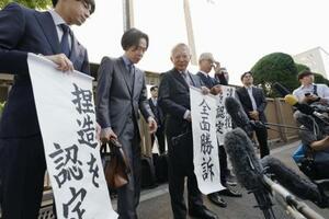 大川原化工機訴訟の東京高裁判決を受け、「全面勝訴」と書かれた紙を手にする大川原正明社長ら=5月、東京高裁前