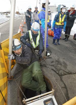 下水道管の緊急点検のためマンホールに入る作業員=2月12日、新潟市秋葉区