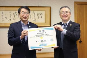 寄付金の目録を手渡す明治安田生命保険の田窪始郎新潟支社長(右)=新潟市役所