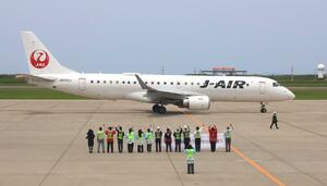 日本航空の新潟-大阪線就航60周年を記念し、新潟発の便を見送る日航関係者ら=1日、新潟市東区の新潟空港