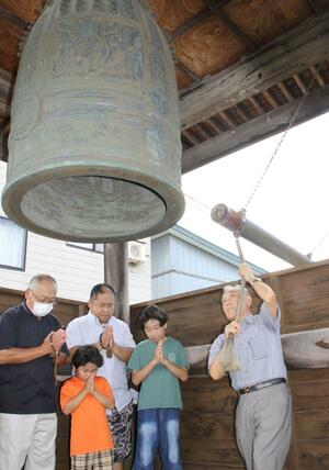 戦没者をしのんで鐘をつき手を合わせる遺族ら=8月15日、妙高市の善照寺