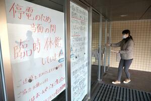 停電で臨時休館している県立図書館。入り口に張り紙があり、職員が来館者への対応に当たっていた=4日、新潟市中央区
