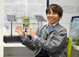 インタビューに答える三枡裕也さん。奥ははやぶさ2の模型=2月10日、神奈川県相模原市