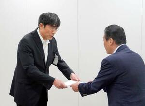 国交省九州運輸局からの改善を指示する文書を受け取る熊本市の井芹和哉交通事業管理者(左)=18日午後、福岡市