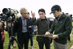 説明を聞きながら釧路湿原周辺にある大規模太陽光発電所の建設予定地を視察するアルピニストの野口健さん(中央)=2日午前、北海道釧路市