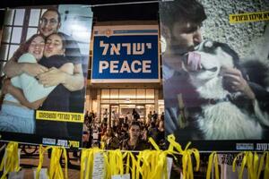 　１２日、イスラエル・テルアビブの広場で、拘束中の人質の写真を見つめる女性（ゲッティ＝共同）