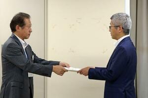 東北電力女川原発敷地内に「乾式貯蔵施設」を設置する計画について、宮城県庁で担当者(左)から回答書を受け取る東北電原子力本部の阿部正信原子力部長=29日午後