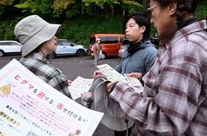 　登山客にヒグマへの注意を呼びかけるチラシを配るＮＰＯのボランティア（右から２人目）＝１０月、札幌市