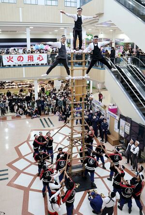 伝統のはしご登りを披露する上越市消防団板倉方面隊の団員=1月12日、上越市富岡のイオン上越店