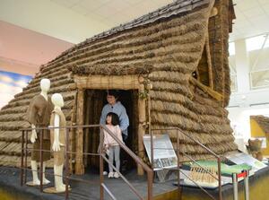 復元された竪穴住居を見て回る来館者=18日、津南町中深見