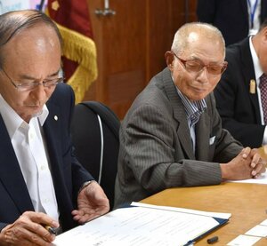 六日町、塩沢、大和の3商工会合併に向けた基本協定調印式に臨む中嶋成夫さん(右)。まちづくりにも尽力した=6月、南魚沼市役所