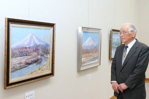 展示作品を見つめる丸岡稔さん。長年にわたって自然を描き続けてきた=長岡市学校町1