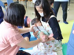 赤ちゃんを優しく抱きかかえる児童=佐渡市畑野