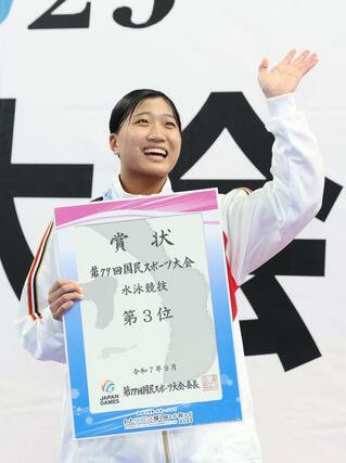 表彰台に立ち、県選手団に向かって笑顔で手を振る神田倫來（新潟第一高）＝滋賀県草津市