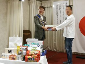 食品などの物資を県フードバンク連絡協議会の小林淳事務局長(右)へ手渡す三条東ロータリークラブの大竹賢一会長(左)=三条市本町3