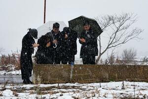 能登半島地震で犠牲になった親族の自宅跡で手を合わせる人たち=1日午後1時58分、石川県珠洲市宝立町