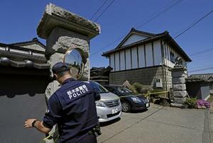 　強盗殺人事件現場の住宅に規制線を張る警察官＝１７日午前、栃木県上三川町