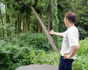 寺に続く道路が崩れた場所を見つめる、立善寺の住職玉岡彰仁さん=8月、石川県門前町浦上