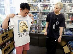 ビンテージTシャツを見る高橋進さん(左)=7月、東京・原宿