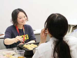たこ焼きを囲んで高校生と談笑する上田夏子さん（左）＝妙高市朝日町１のまちなか＋