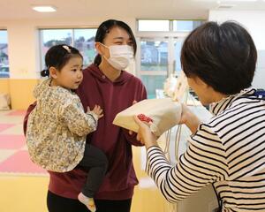 職員から「おぢやつつみ」を受け取る保護者=小千谷市城内4
