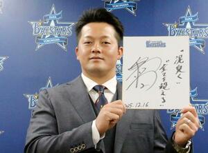 契約交渉を終え、記者会見で色紙を手にするDeNAの牧=16日、横浜市の球団事務所