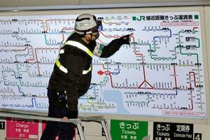 値上げが反映された運賃表を確認する作業員=14日未明、JR東京駅