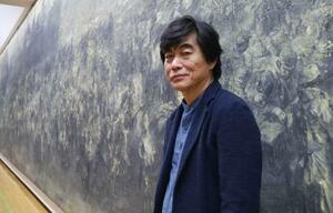 油絵「一九四六」の前に立つ中国人画家の王希奇さん=6日午後、福岡市