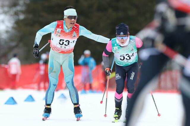 成年男子４０キロリレー　１走宮尾祐司（左・髙田自衛隊）が２走我田柊（日大）へリレー＝１７日、青森県大鰐町