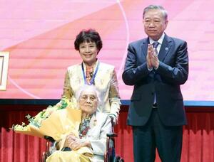 　ベトナム最高指導者トー・ラム共産党書記長（右）から「労働英雄」の称号を授与されたグエン・ティ・ビン元国家副主席（左手前）＝２５日（ＶＮＡ＝共同）