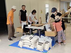食品を配布する会場で作業に当たるフードバンクにしのメンバーら=西区役所
