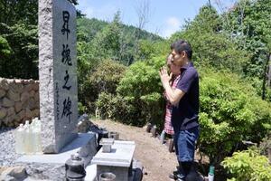 慰霊碑「昇魂之碑」前で手を合わせるJR東日本職員の男性ら=7月、群馬県上野村