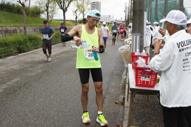 
４０・７キロ地点。最後のセルフ給水所で、立ち止まってマイボトルに給水するランナー＝12日、新潟市中央区
