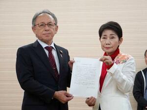 　山内末子県議（右）から沖縄県知事選への出馬要請書を受け取る玉城デニー知事＝１３日午後、那覇市