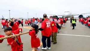 イベントで、綱でジェット機を引っ張る人たち=13日午前、成田空港