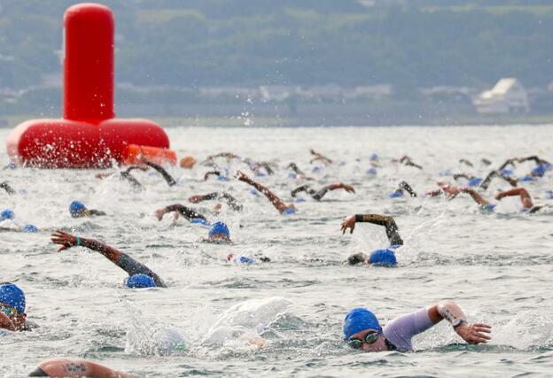 波の穏やかな真野湾を懸命に泳ぐ選手たち＝９月１日、佐渡市
