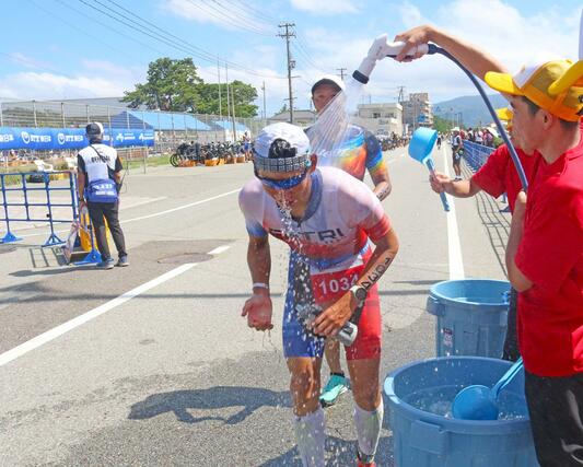 ボランティアらに冷水を掛けてもらいながら懸命に走る選手たち＝９月１日、佐渡市