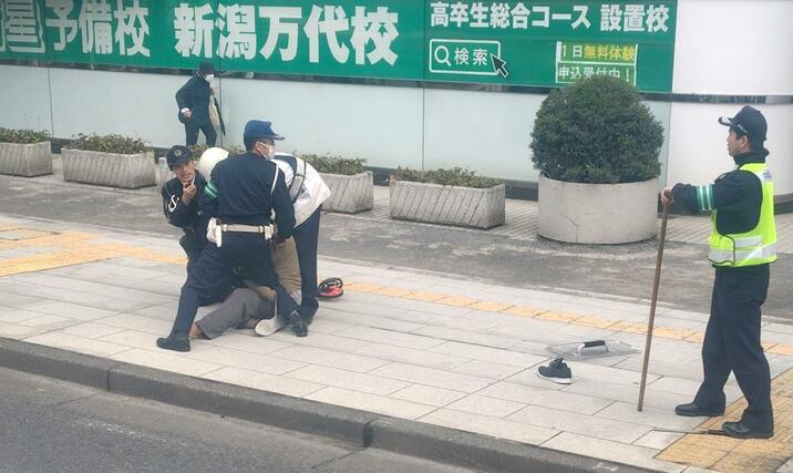 警察に確保される男＝１６日、新潟市中央区万代４