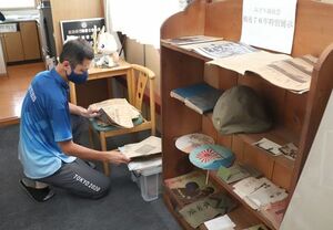 空き家で発見された戦時中の品々と、展示した善養寺貴洋さん=田上町羽生田