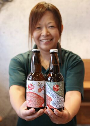 かんずりを使ったクラフトビール「風虎」の瓶入りを手にする大越景子さん=上越市の「SMOKE&BEER ORION」