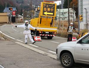 冬の備えを呼びかけるため、国道17号を通行する車両を誘導する南魚沼署員ら=湯沢町神立