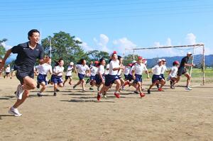 セキノ興産陸上競技部の選手から走り方を学ぶ葛巻小の4年生=見附市反田町