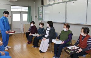 地域住民が刈羽中学校の卒業生に手作りコサージュを手渡した=刈羽村刈羽