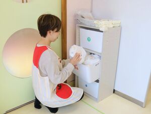 サブスクリプションサービスを導入している私立こども園で、配備されたおむつを取り出す保育士=新潟市中央区南出来島1
