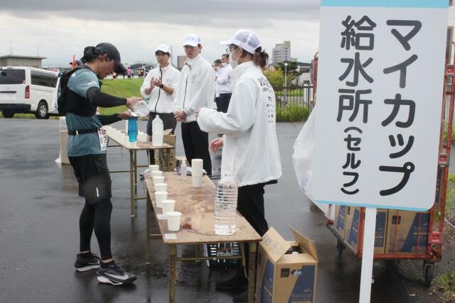 フルマラソン31・８キロに設けられたセルフ給水所。テーブルに並んだペットボトルの飲料水をマイボトルに入れるランナー＝12日、新潟市西区の西川排水機場近く