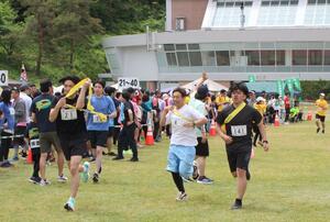 リレーマラソンでたすきをつなぐ参加者たち=5月12日、長岡市の国営越後丘陵公園