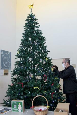 ツリーにリボンを結ぶ点灯式の参加者=上越市高土町3